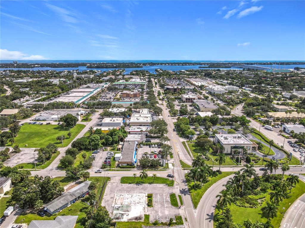An aerial view shows a commercial area with parking lots, buildings, and surrounding greenery — 810 21ST STREET, VERO BEACH, FL