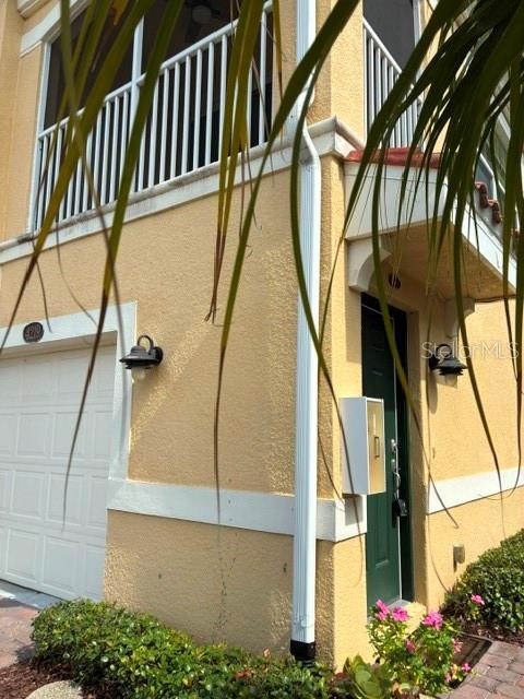 A yellow stucco building exterior features a garage, a screened balcony, and a green door — 4219 FRONTIER WAY UNIT 105, OSPREY, FL