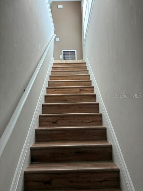 A straight staircase with wood-look steps leads up to a landing with a wall vent — 4219 FRONTIER WAY UNIT 105, OSPREY, FL