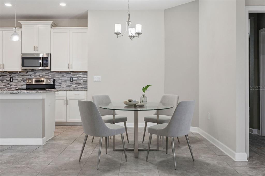 A dining room features a white table, six blue patterned chairs, and a coastal painting — 3464 EMBERS LANE, CLERMONT, FL