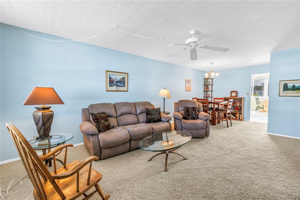 A living room features light blue walls, beige carpet, a ceiling fan, and brown furniture — 4715 BAY STREET NE UNIT 320, ST PETERSBURG, FL