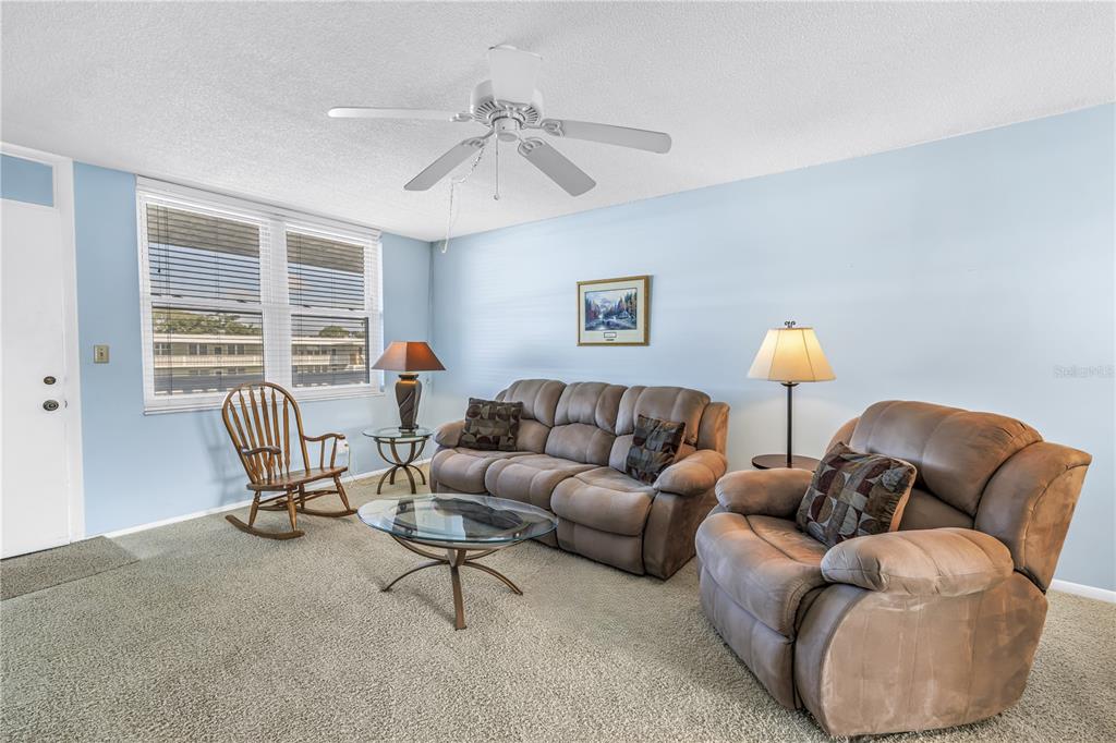 A kitchen with white cabinets and appliances features a dining area with large windows — 4715 BAY STREET NE UNIT 320, ST PETERSBURG, FL