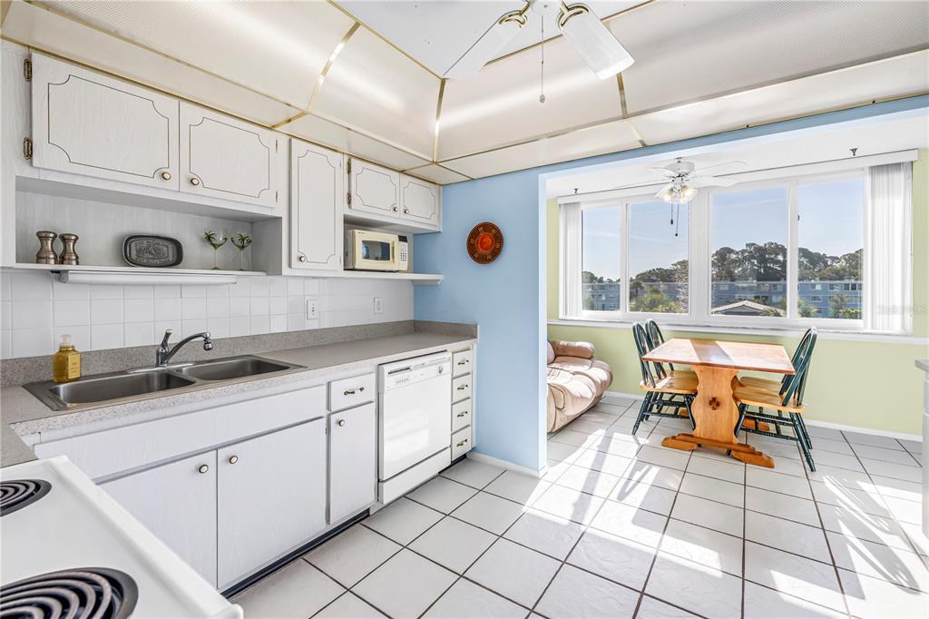 A dining area with a tan sofa, wooden table, dark chairs, and large windows — 4715 BAY STREET NE UNIT 320, ST PETERSBURG, FL