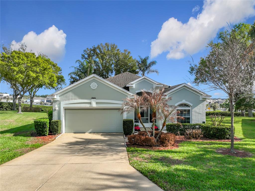 A light green single-story house with a two-car garage and a landscaped front yard — 4334 HAMMERSMITH DRIVE, CLERMONT, FL