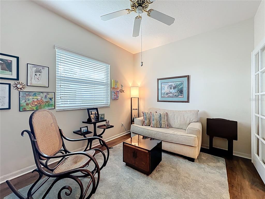 A small living room features a rocking chair, a beige sofa, and a ceiling fan — 4334 HAMMERSMITH DRIVE, CLERMONT, FL