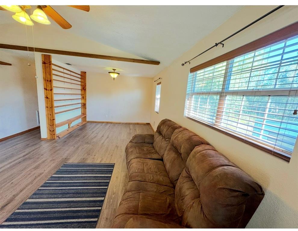 A living room features wood-look flooring, a brown sofa, and a decorative wooden room divider — 12109 PLATANO DRIVE, PUNTA GORDA, FL
