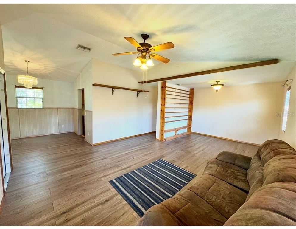 A living room features wood-look flooring, a ceiling fan, a wooden room divider, and a sofa — 12109 PLATANO DRIVE, PUNTA GORDA, FL