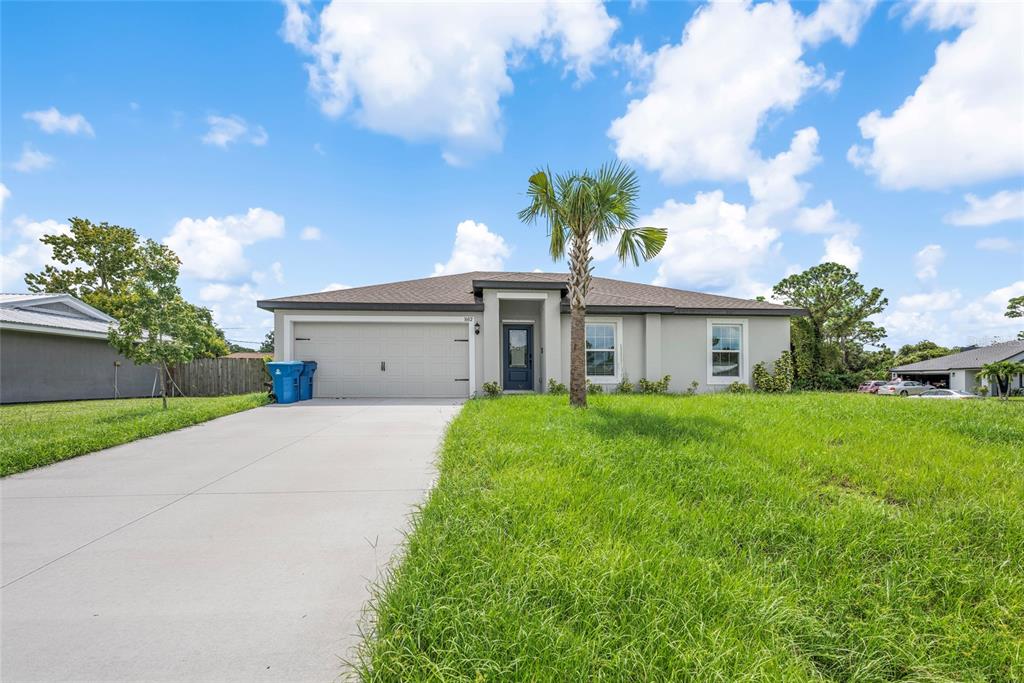 A single-story house with a concrete driveway, a palm tree, and a two-car garage — 1602 SALADINO STREET SE, PALM BAY, FL
