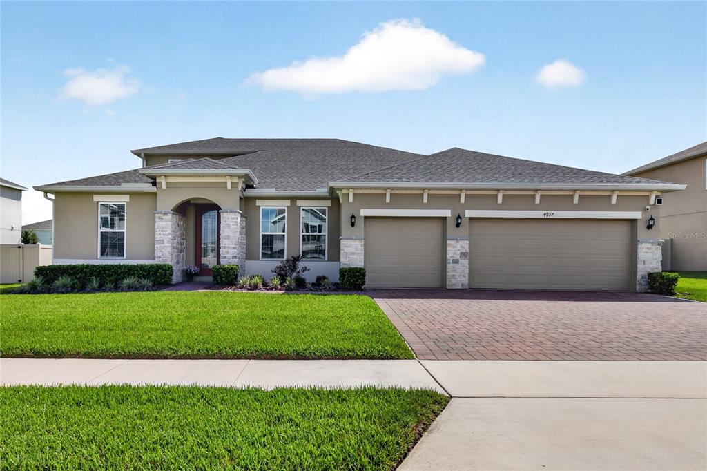 A single-story house with a stone-accented entryway, a three-car garage, and a paved driveway — 4937 GOLDEN ZENITH WAY, MOUNT DORA, FL
