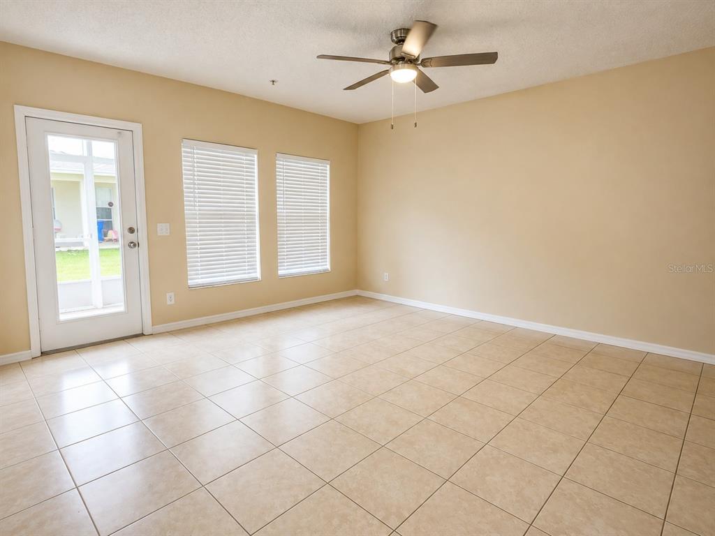 An empty room with beige walls, tile flooring, a ceiling fan, and a glass door — 2039 CYPRESS BAY BOULEVARD, KISSIMMEE, FL