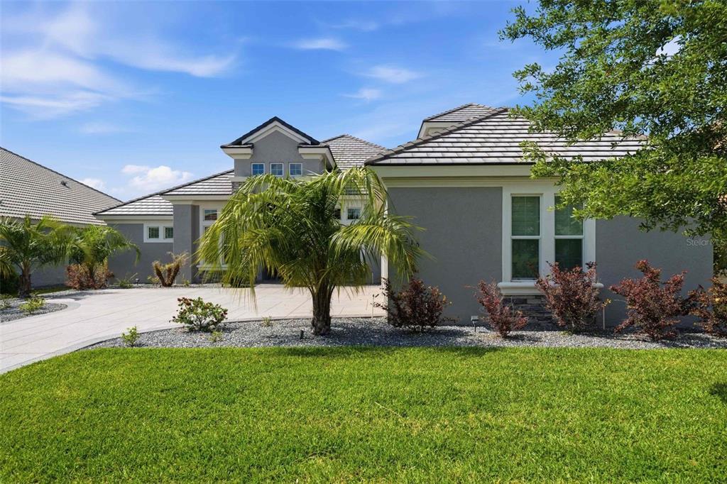 A gray single-story house with a tiled roof, palm tree, and paved driveway — 2210 N PEAKVIEW LOOP, HERNANDO, FL