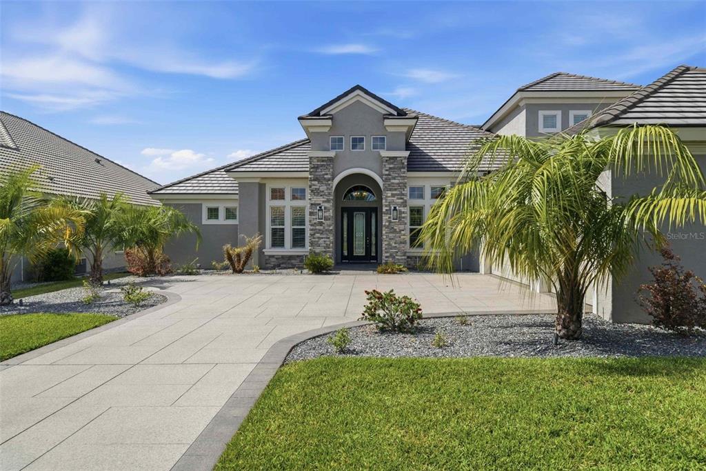 A single-story house with a stone-accented entryway, a paved driveway, and palm trees — 2210 N PEAKVIEW LOOP, HERNANDO, FL