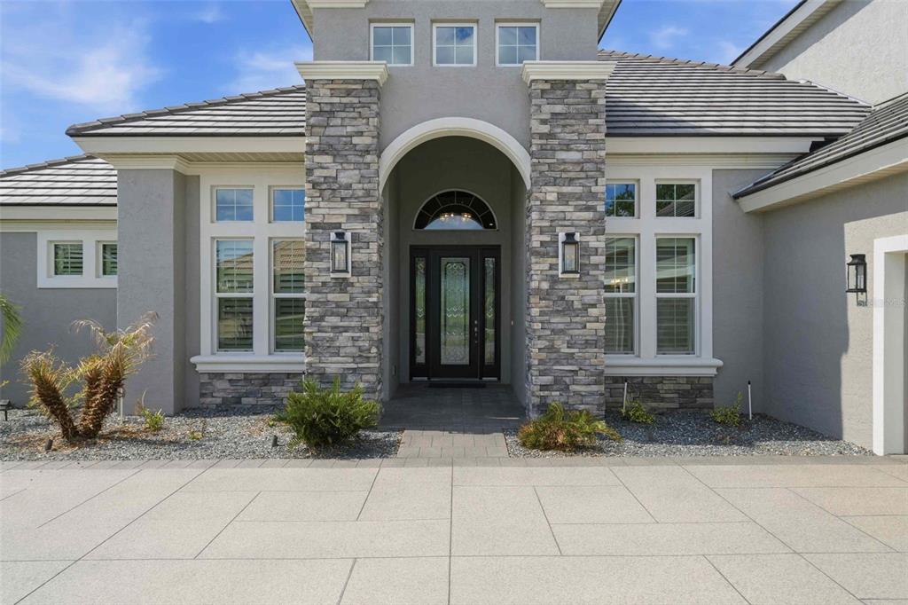 A stone-accented entryway features a dark glass front door under a large arched portico — 2210 N PEAKVIEW LOOP, HERNANDO, FL