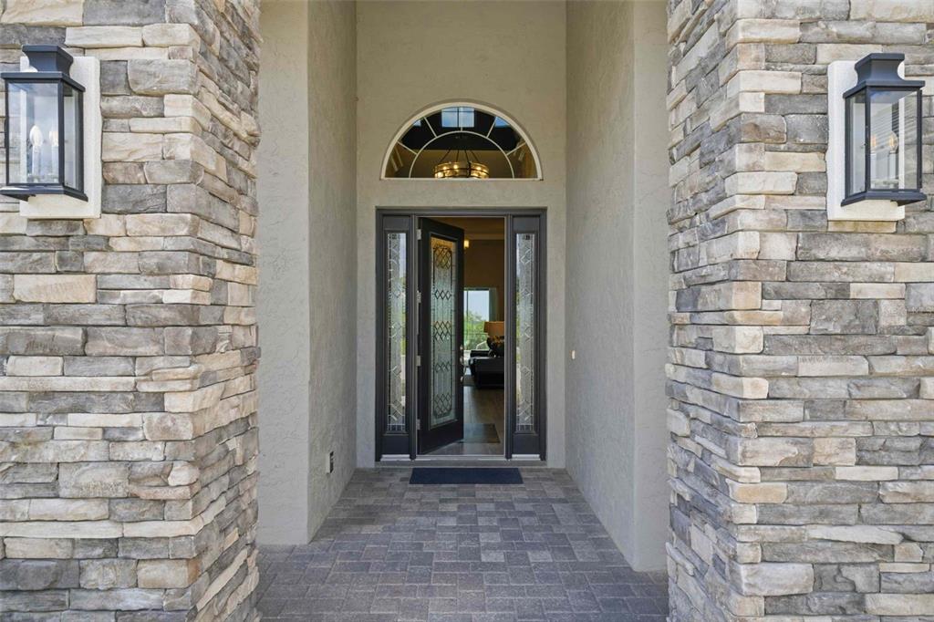 A stone-clad entryway features a dark front door with glass inserts and a transom window — 2210 N PEAKVIEW LOOP, HERNANDO, FL