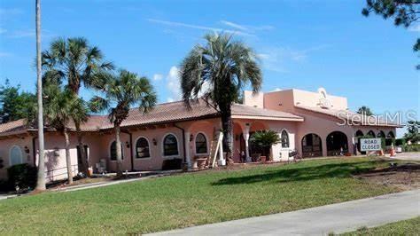 A single-story peach-colored building with a tiled roof and palm trees on a grassy lot — 1532 W SCHWARTZ BOULEVARD, LADY LAKE, FL