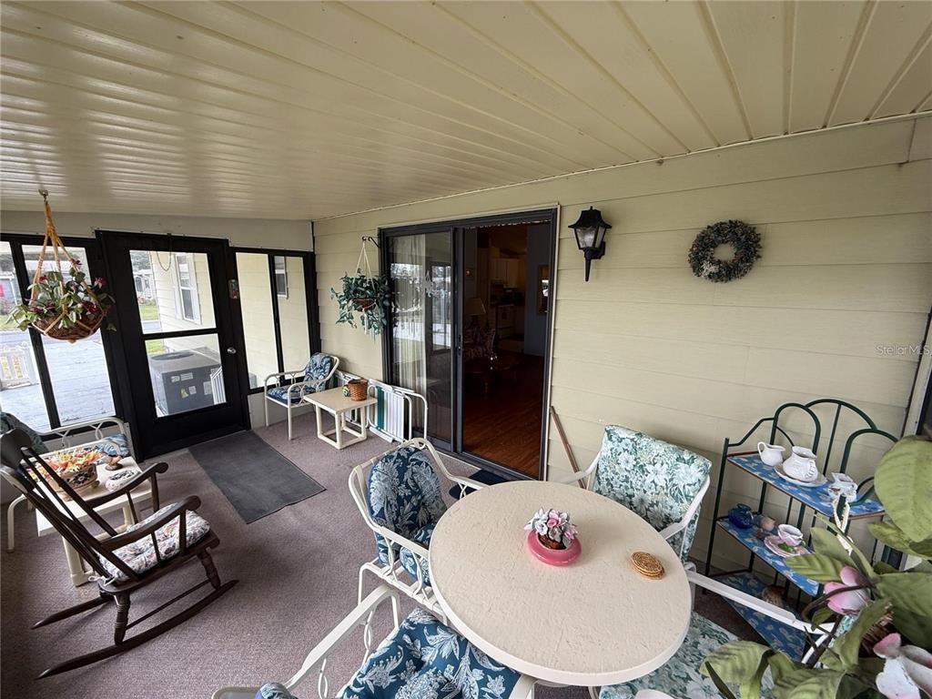 A covered porch features outdoor furniture, a sliding glass door, and light-colored siding — 1532 W SCHWARTZ BOULEVARD, LADY LAKE, FL