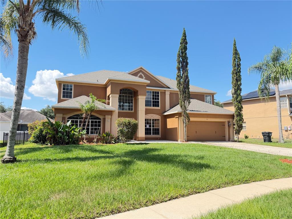 A two-story suburban house with a tan stucco exterior, a garage, and a front lawn — 706 STRIHAL LOOP, WINTER GARDEN, FL