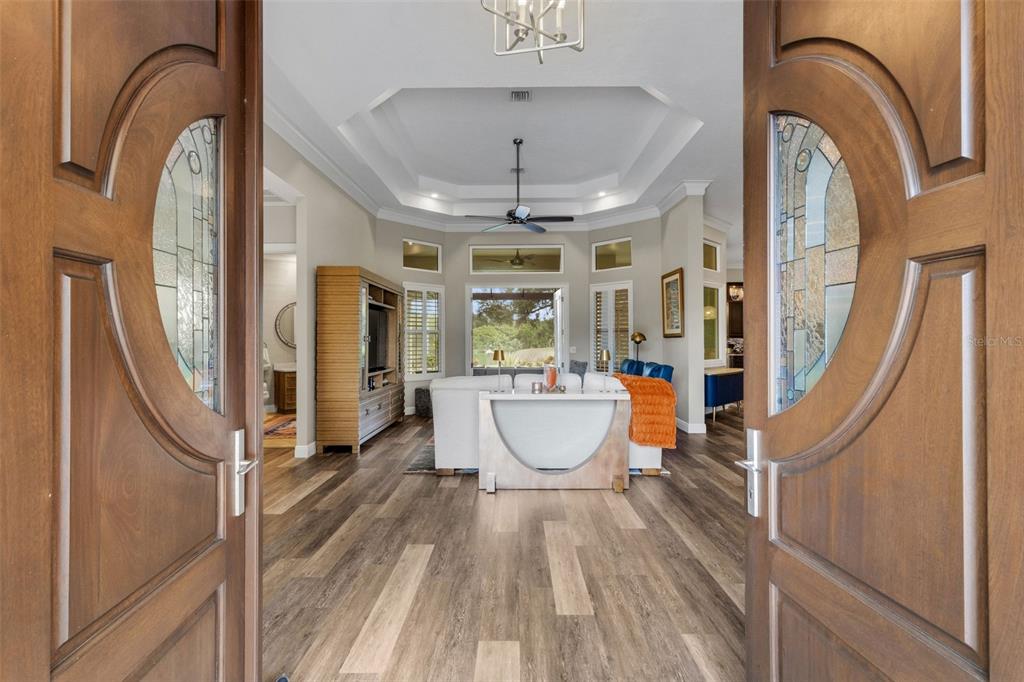 A foyer features double wood doors, wood-look flooring, a white console table, and wall art — 7732 DONALD ROSS ROAD W, SARASOTA, FL
