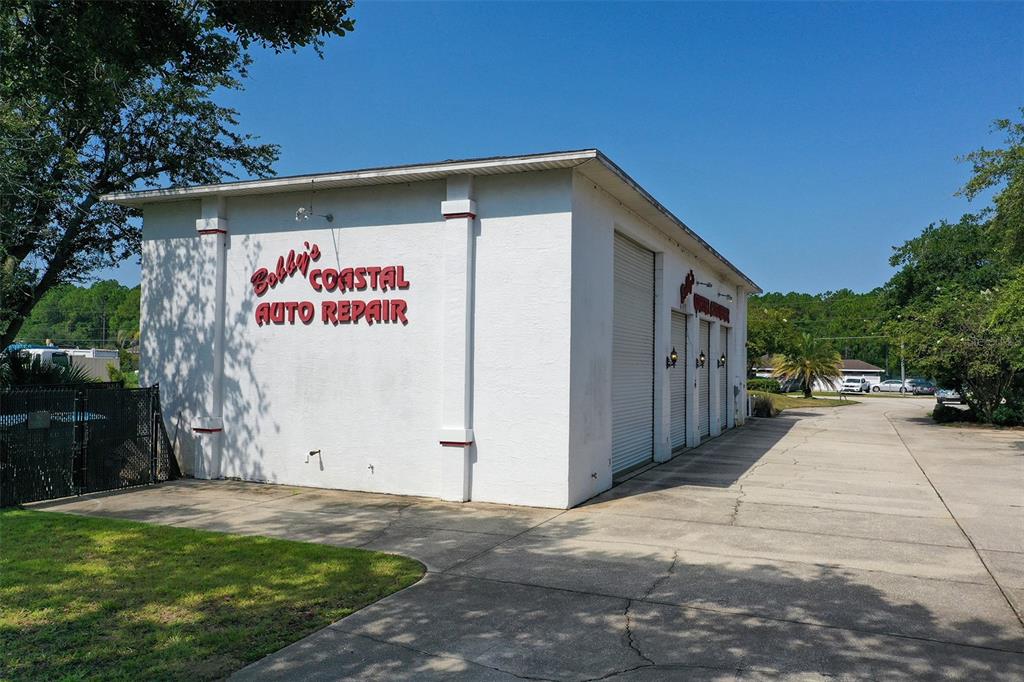 A white commercial building with roll-up garage doors sits on a paved lot — 10 ENTERPRISE DRIVE, BUNNELL, FL