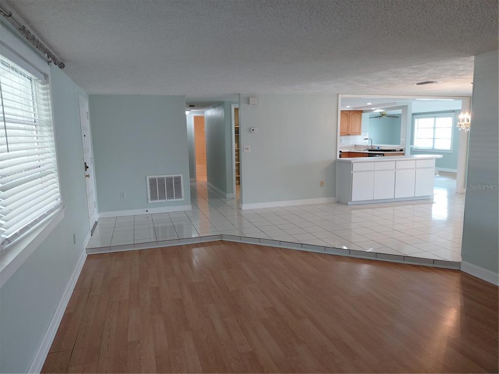A room with white tile flooring, a crystal chandelier, and a mirrored wall — 4113 STAR ISLAND DRIVE, HOLIDAY, FL