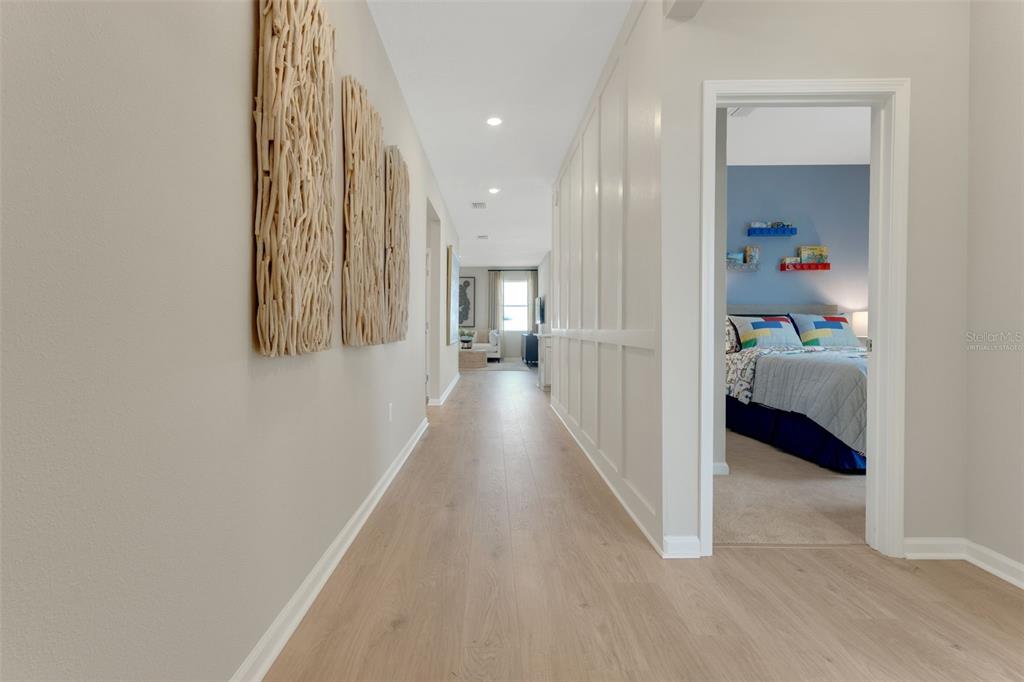 A hallway with light wood flooring leads to a bedroom and a distant living area — 296 MEREDITH BOULEVARD, WINTER HAVEN, FL