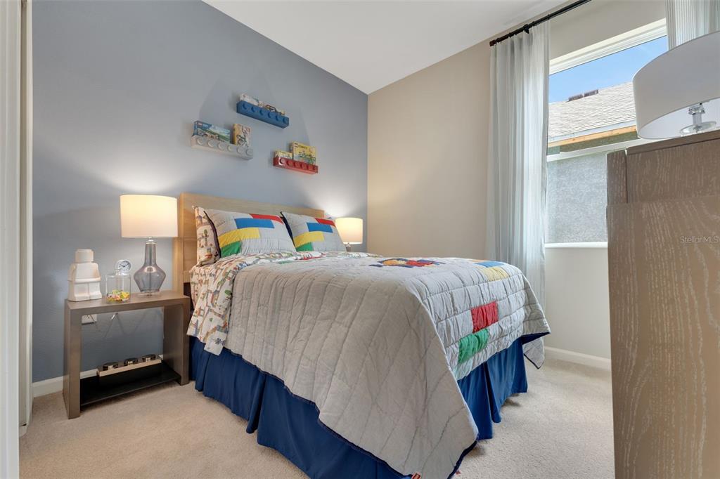 A bedroom features a bed with Lego-themed bedding, a blue accent wall, and floating shelves — 296 MEREDITH BOULEVARD, WINTER HAVEN, FL