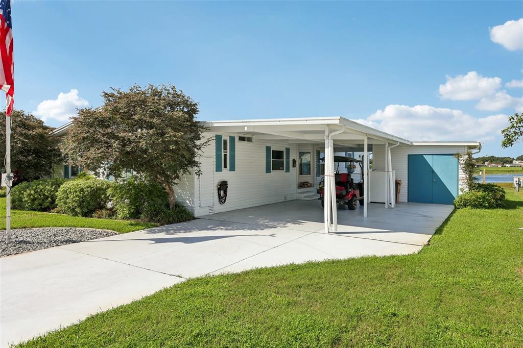 A single-story house with a carport, a flag pole, and a gravel landscaping bed — 24941 PINE HILL, LEESBURG, FL