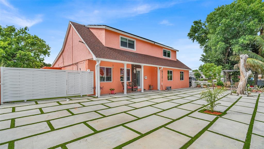 A two-story peach-colored house features a large paved patio with grass between the concrete pavers — 8301 LOPEZ DRIVE, TAMPA, FL