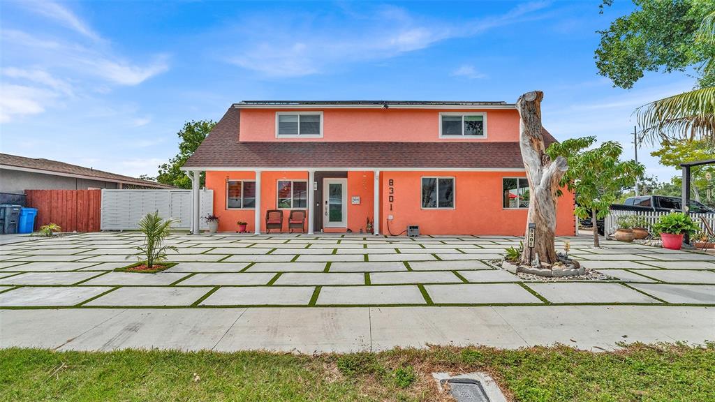 A two-story orange house features a large concrete paver driveway with grass inlays — 8301 LOPEZ DRIVE, TAMPA, FL