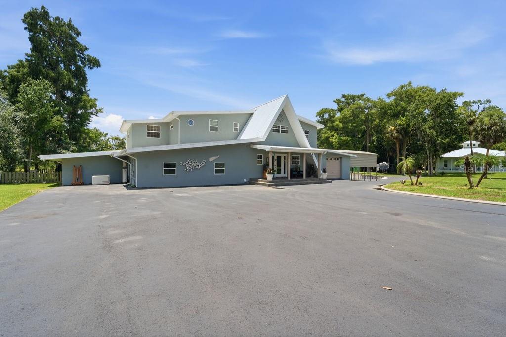A living room features a green sectional sofa, wood-look tile flooring, and a wooden staircase — 220 BRANDY COURT, DELTONA, FL