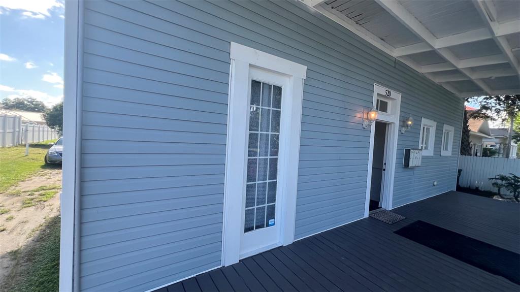 A blue-sided house features a covered wooden porch with a glass-paneled door and windows — 520 S BROADWAY AVENUE, BARTOW, FL