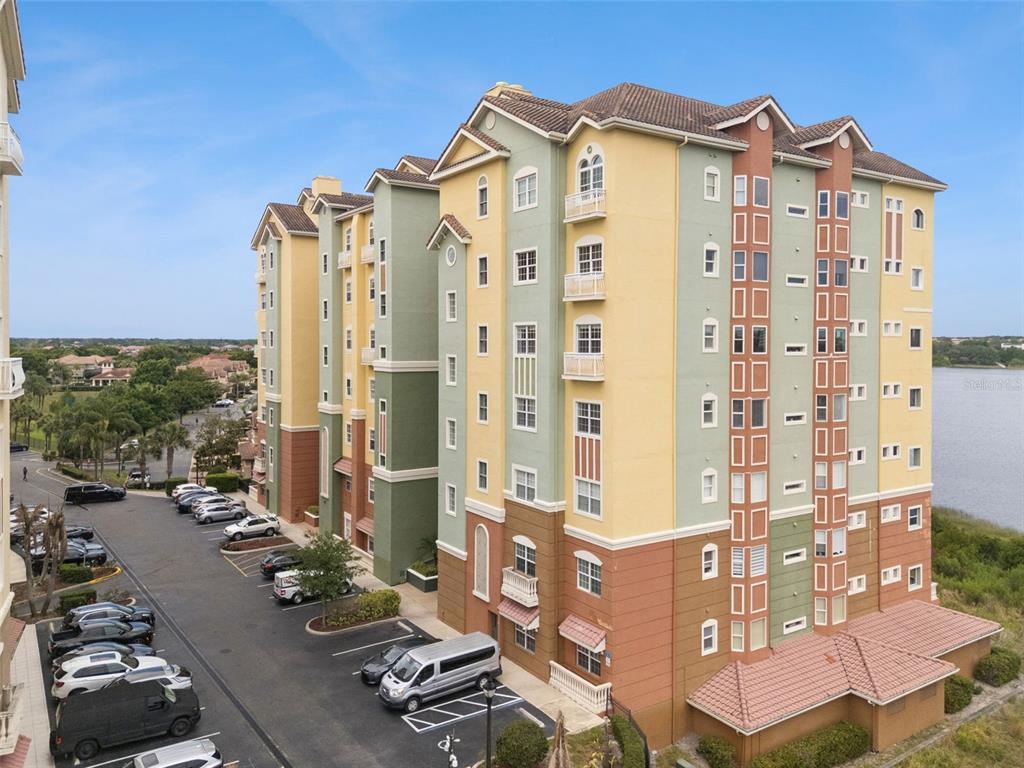 An exterior view of a multi-story apartment building with a parking lot and lake — 8743 THE ESPLANADE UNIT 34, ORLANDO, FL