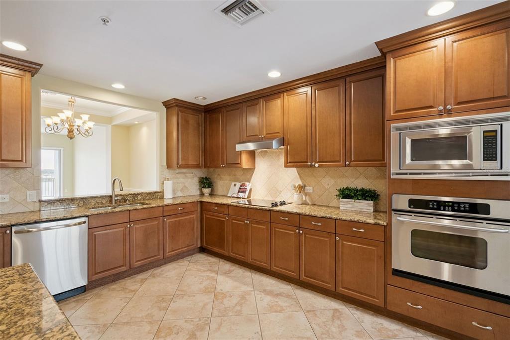 A kitchen with wood cabinets, granite countertops, stainless steel appliances, and tile flooring — 8743 THE ESPLANADE UNIT 34, ORLANDO, FL