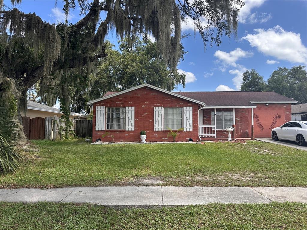 A single-story red brick house features white shutters, a front porch, and a grassy lawn — 8848 OAK CIRCLE, TAMPA, FL