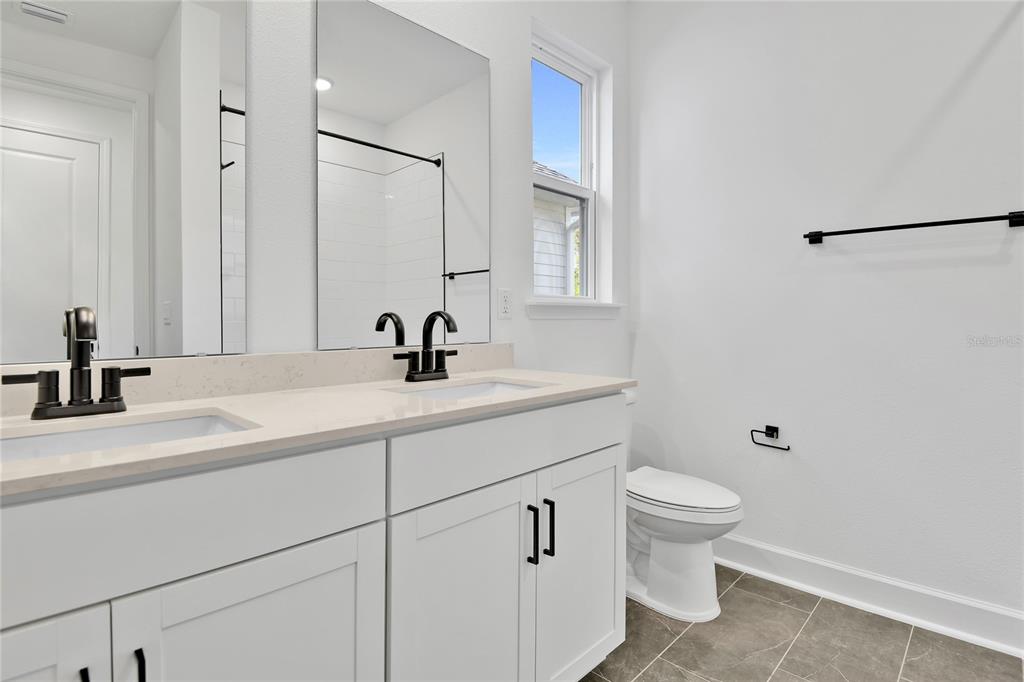 A bathroom features a white bathtub, green and white subway tile, and textured gray wallpaper — 207 THORNBERRY WAY, PALM COAST, FL