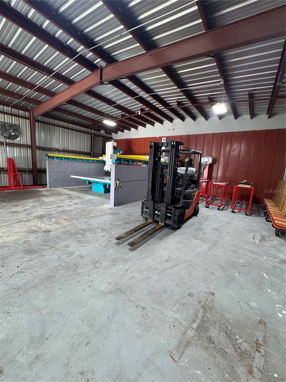 An industrial warehouse space features a forklift, a large stone-cutting machine, and red metal walls — 4825 N LAUBER WAY, TAMPA, FL