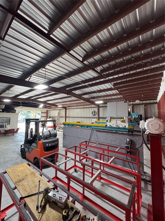 A warehouse interior features a Toyota forklift, metal framing, and industrial machinery under a metal roof — 4825 N LAUBER WAY, TAMPA, FL
