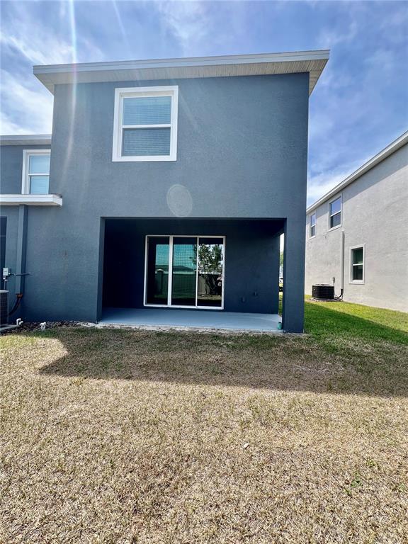 The rear exterior of a two-story house features a covered patio and sliding glass doors — 32557 TURTLE GRACE LOOP, WESLEY CHAPEL, FL