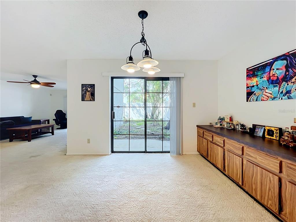 A covered carport leads to a front door with a yellow wall and light blue siding — 7488 WHISPERWOOD DRIVE UNIT 28, WINTER PARK, FL