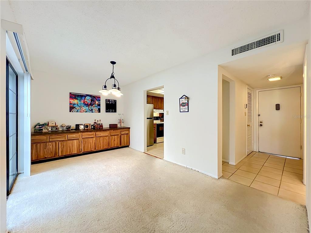 A covered carport features a yellow wall, an orange front door, and a storage closet — 7488 WHISPERWOOD DRIVE UNIT 28, WINTER PARK, FL