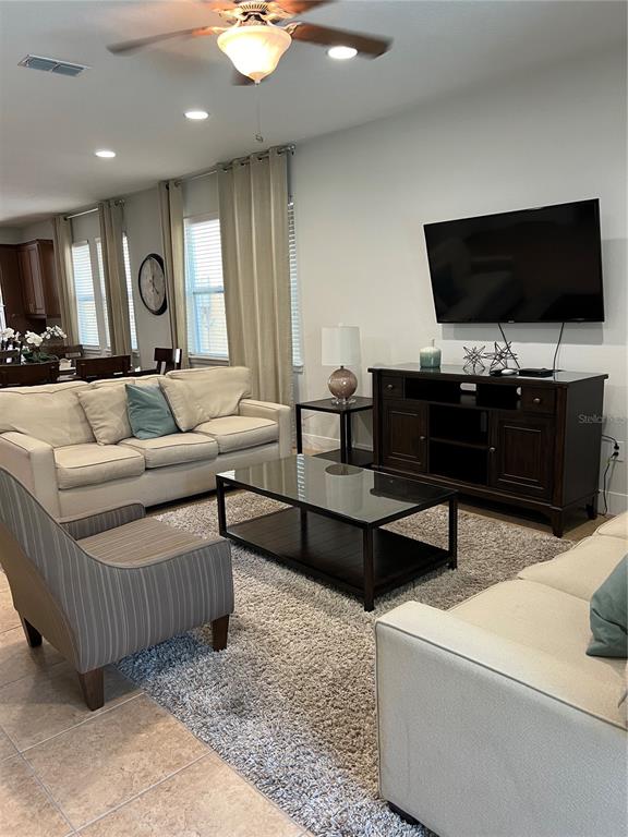 A living room features a beige sofa, a striped armchair, and a dark wood media console — 370 LASSO DRIVE, KISSIMMEE, FL