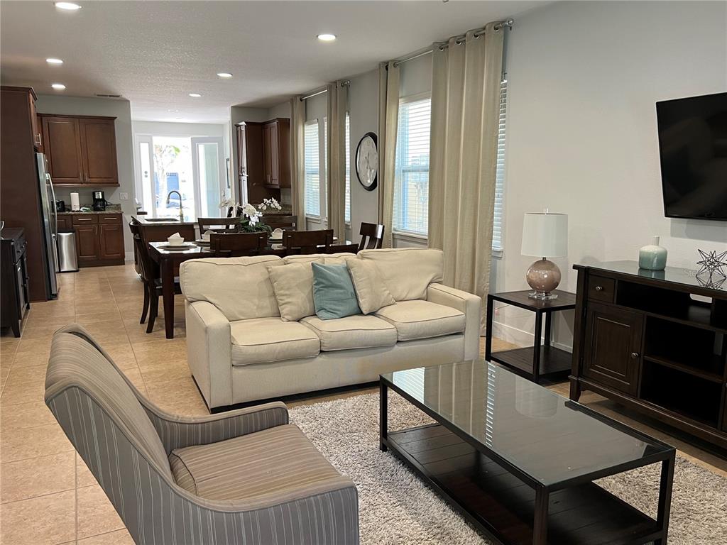 An open-concept living and dining area features tile flooring, neutral furniture, and dark wood cabinetry — 370 LASSO DRIVE, KISSIMMEE, FL