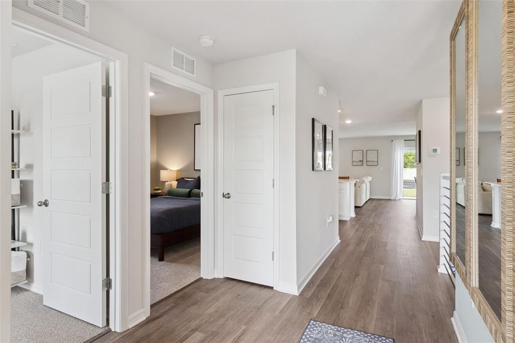 A hallway with wood-look flooring leads past two white doors toward an open living area — 1080 BEAR HAMMOCK DRIVE, UMATILLA, FL