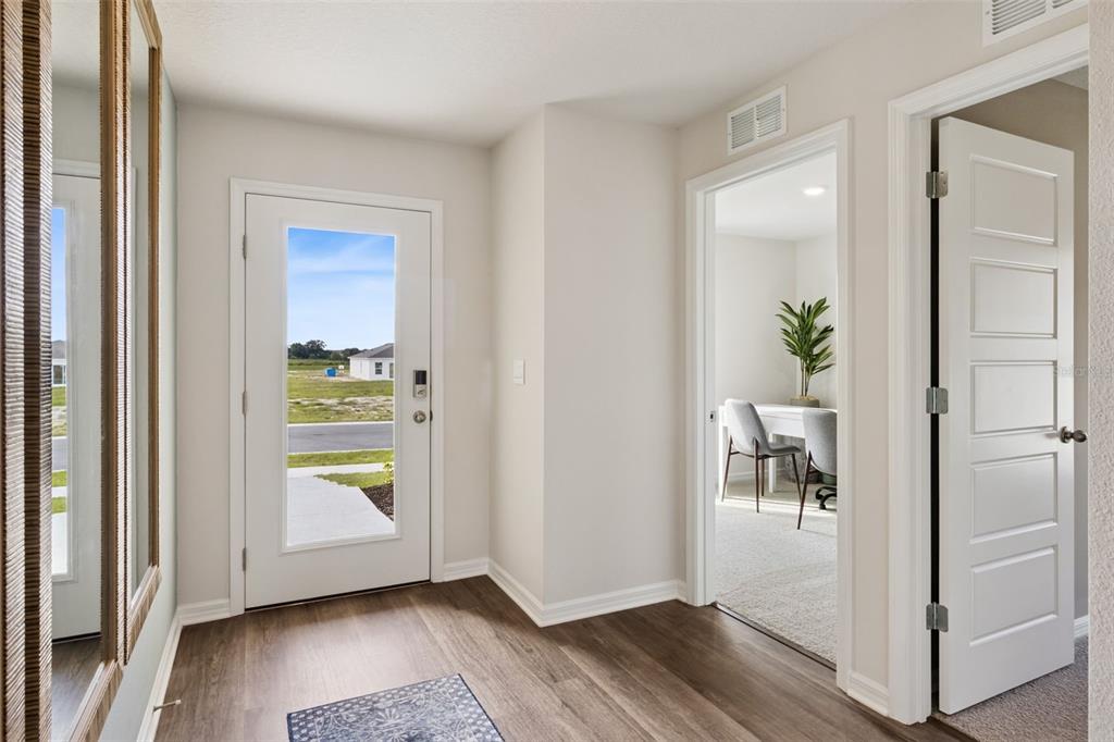 An entryway with wood-look flooring, a glass-paneled front door, and a doorway leading to an office — 1080 BEAR HAMMOCK DRIVE, UMATILLA, FL