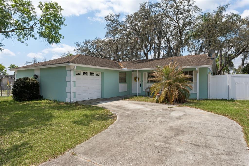 A light green single-story house with a white garage door and a concrete driveway — 502 AVOCADO CIRCLE, BRANDON, FL