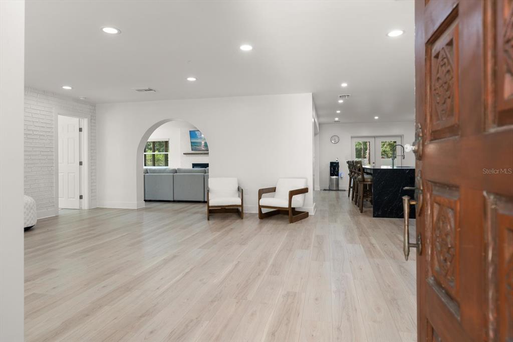 An open-concept living area features light wood floors, white walls, and a kitchen island — 13366 108TH AVENUE, LARGO, FL