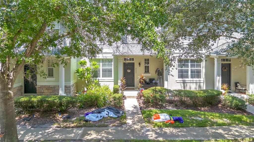 The exterior of a multi-unit townhouse features light-colored siding, stone accents, and front entryways — 4620 CAPITAL BOULEVARD, ST CLOUD, FL