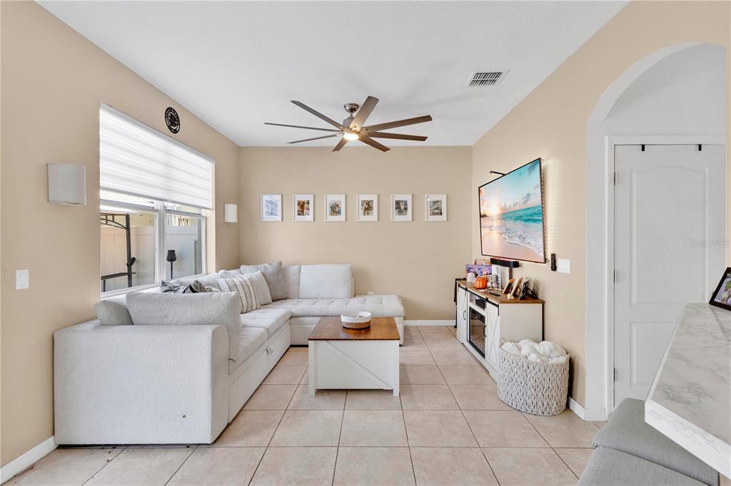 A living room features a white sectional sofa, a wooden coffee table, and a wall-mounted television — 4620 CAPITAL BOULEVARD, ST CLOUD, FL
