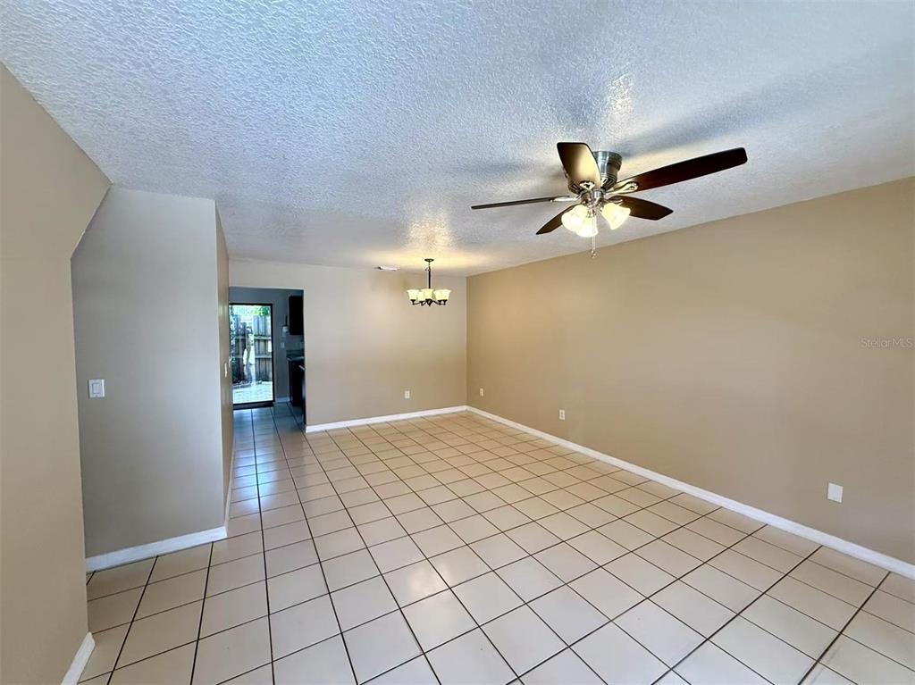 An empty room with beige walls, a tiled floor, a ceiling fan, and a chandelier — 3370 CEDAR SPRINGS PLACE UNIT 156, WINTER PARK, FL