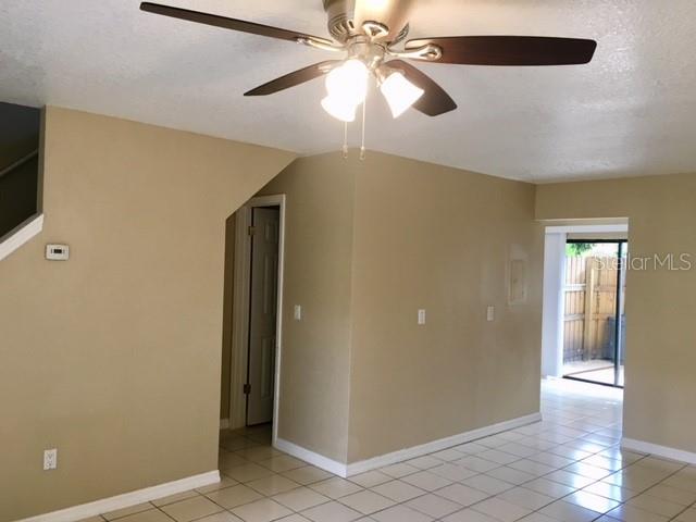 A room with beige walls, a ceiling fan, and white tile flooring leading to a patio — 3370 CEDAR SPRINGS PLACE UNIT 156, WINTER PARK, FL